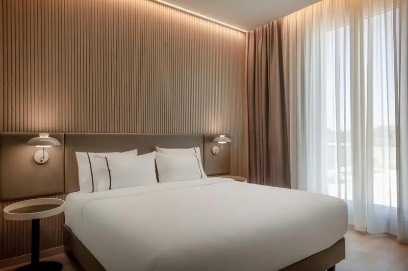 Une chambre lumineuse avec un grand lit et des rideaux.