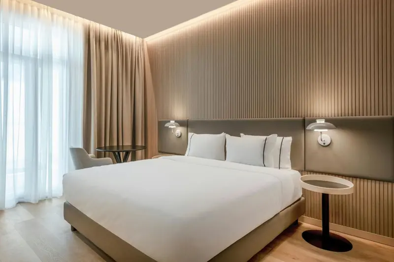 Une chambre moderne avec un grand lit et des rideaux beiges.