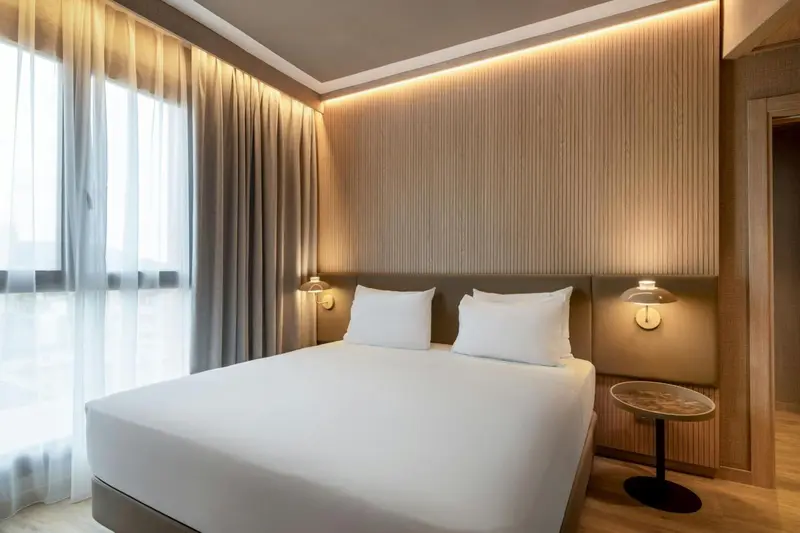 Une chambre moderne avec un grand lit et des rideaux clairs.