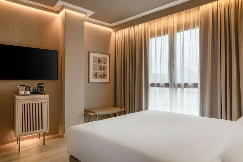 Une chambre lumineuse avec un grand lit et de larges rideaux.