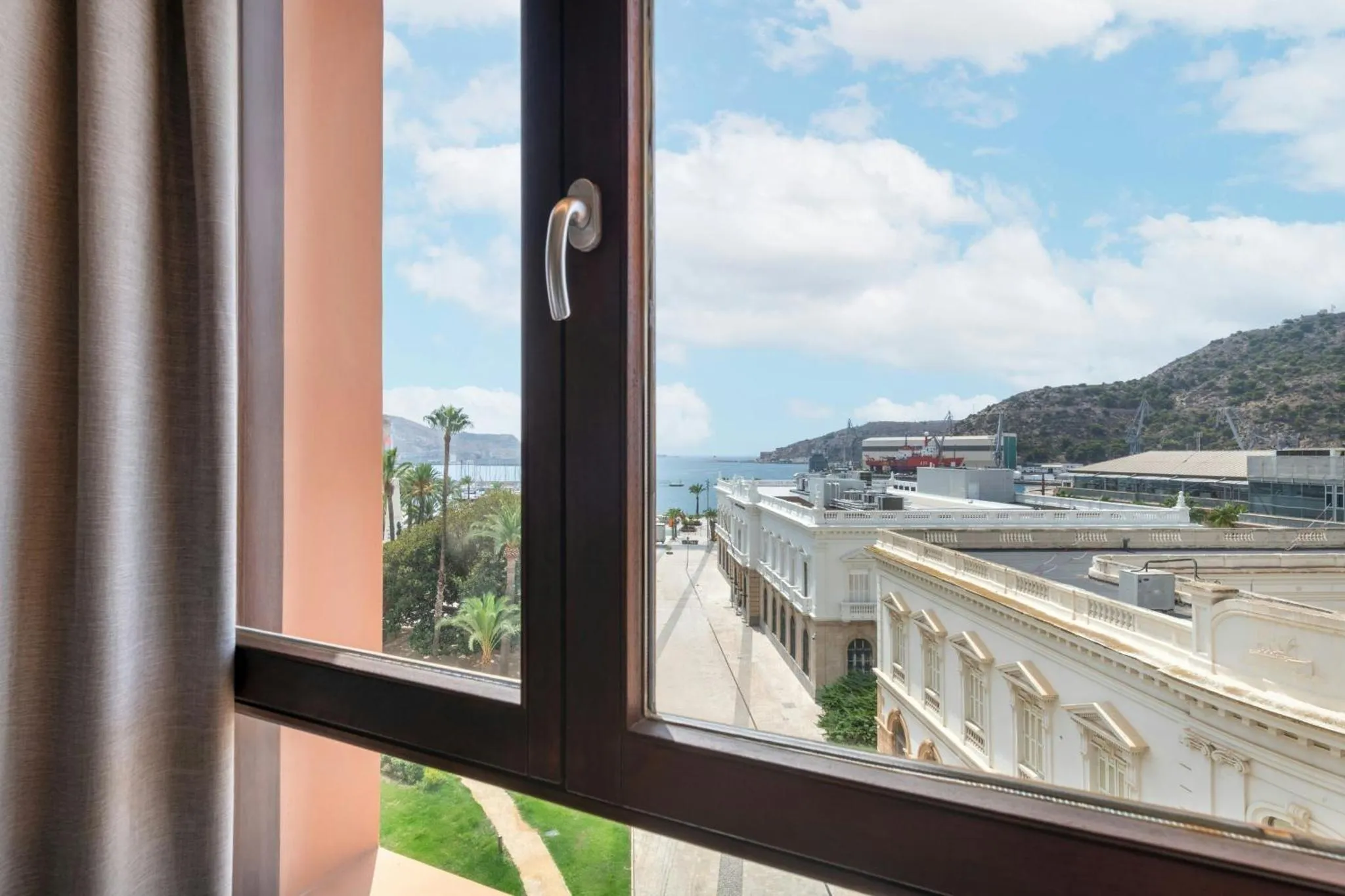 Vue sur la mer et les montagnes depuis une fenêtre.