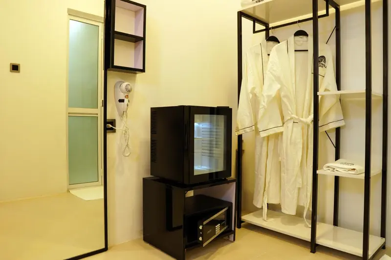 Une chambre d'hôtel lumineuse avec un mini-réfrigérateur et des peignoirs.