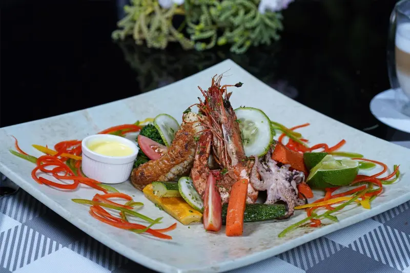Assiette de fruits de mer colorée avec légumes et sauce.