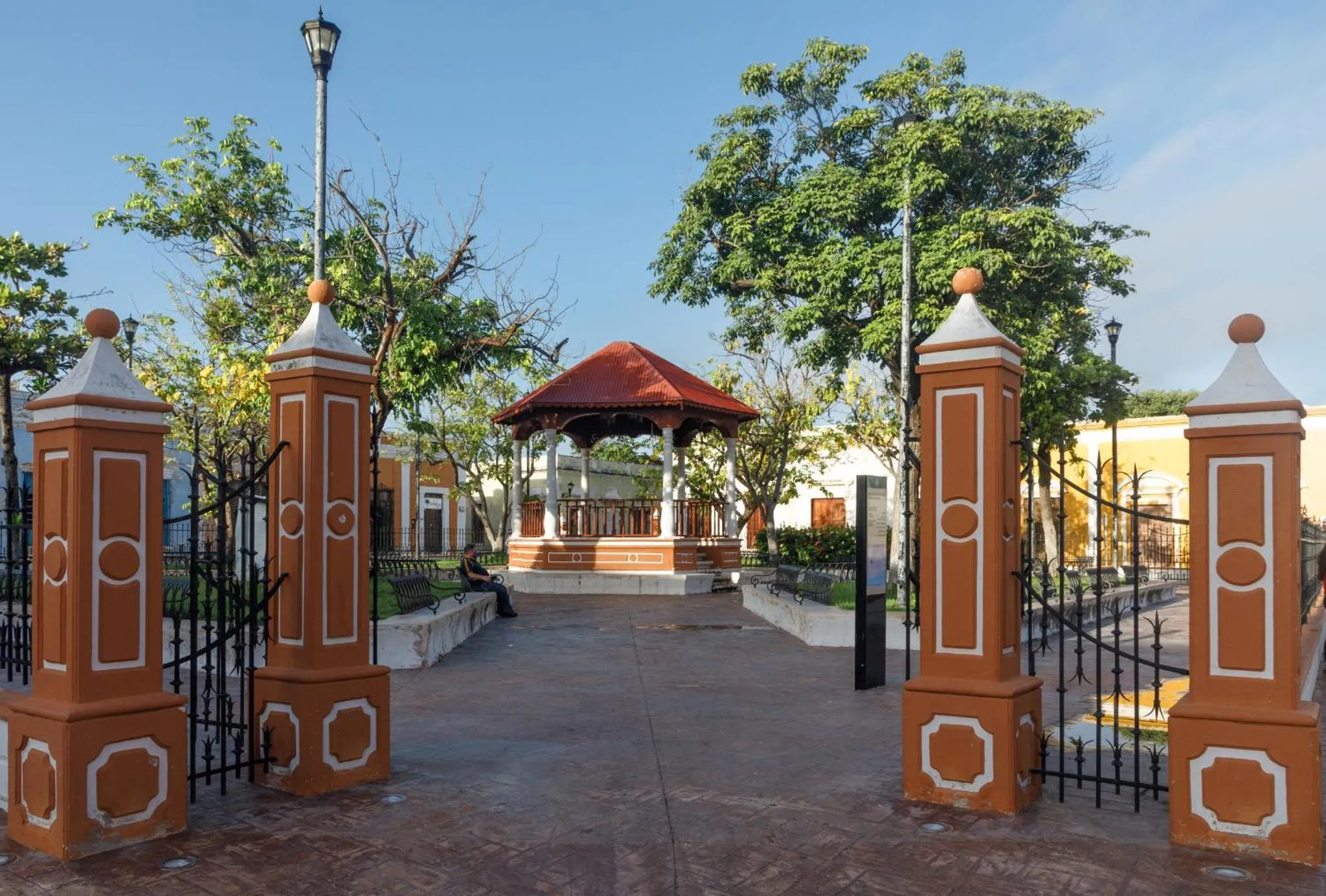 Entree d'un parc avec des piliers decoratifs et une structure abritant un espace de repos.