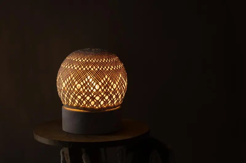 Lampe décorative en métal ajouré posée sur une petite table.