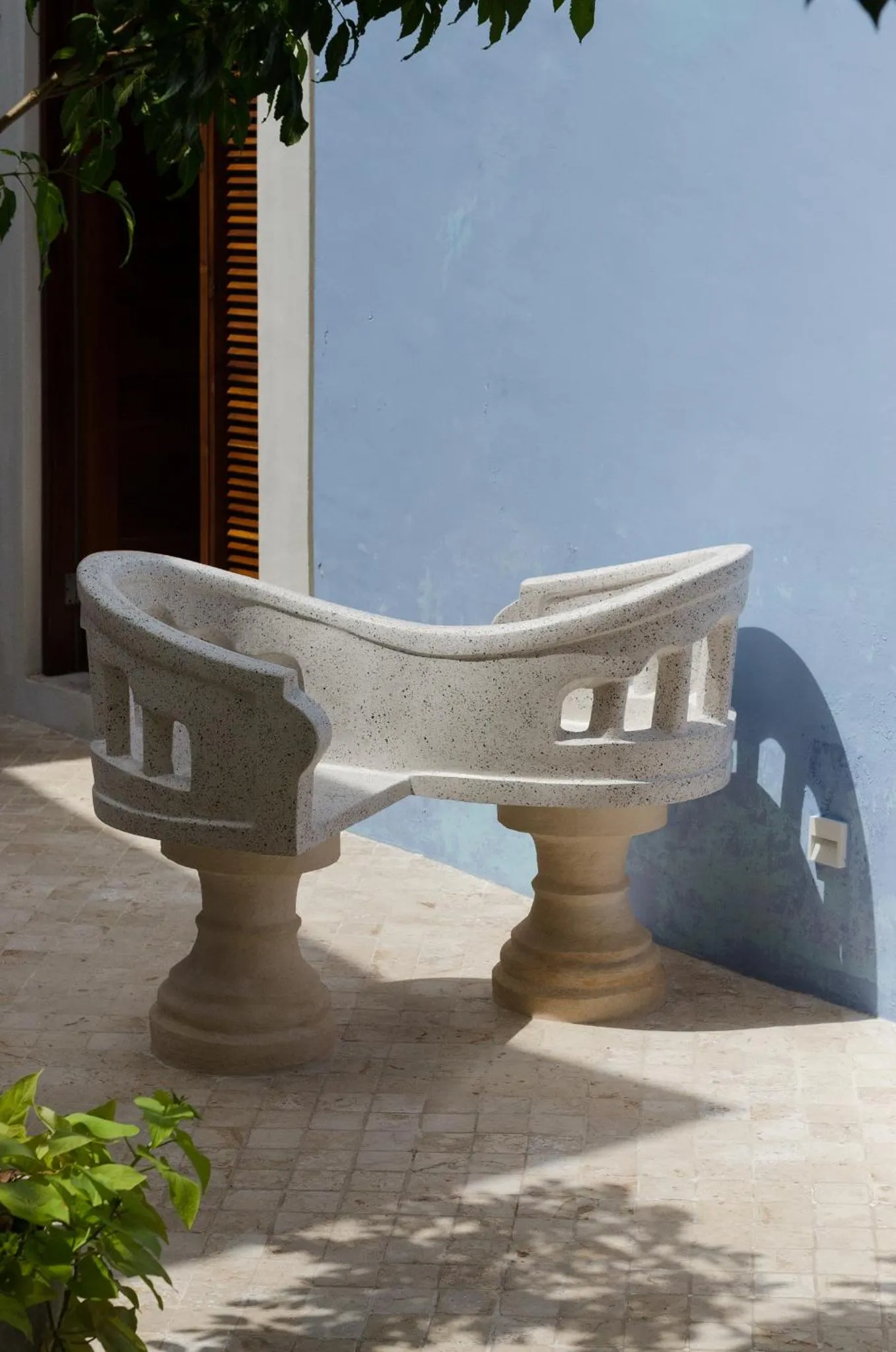 Banc en pierre sur une terrasse ombragée.