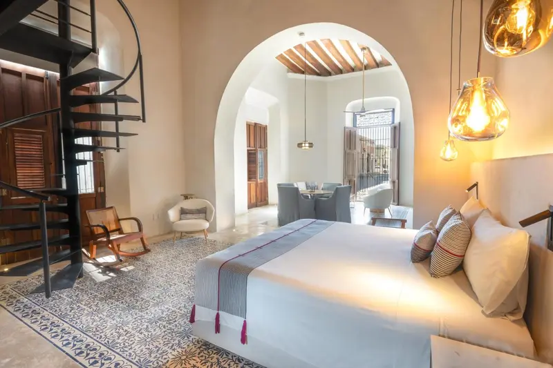 Une chambre lumineuse avec un lit confortable et un escalier en colimaçon.