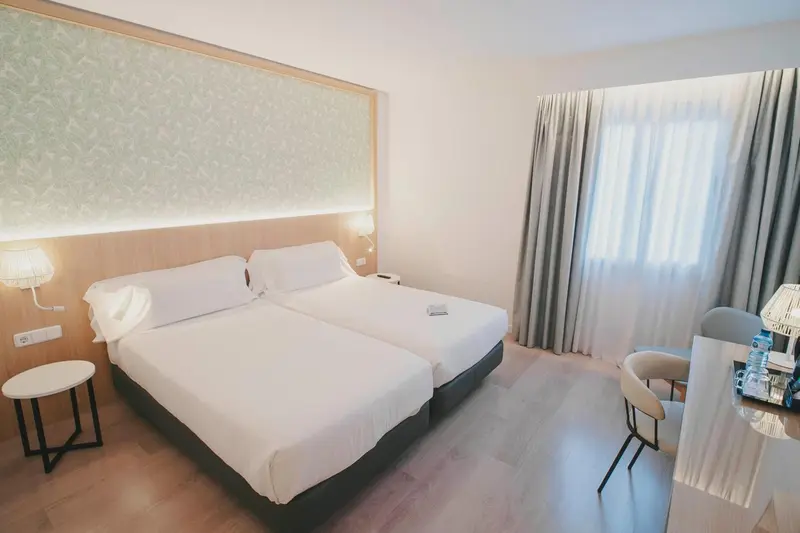 Une chambre lumineuse avec un grand lit et un coin lecture.