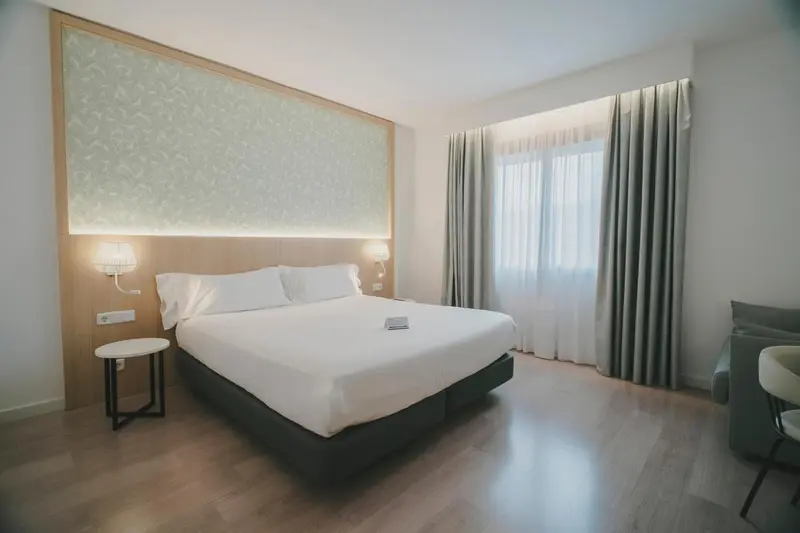 Une chambre lumineuse avec un grand lit et des rideaux.