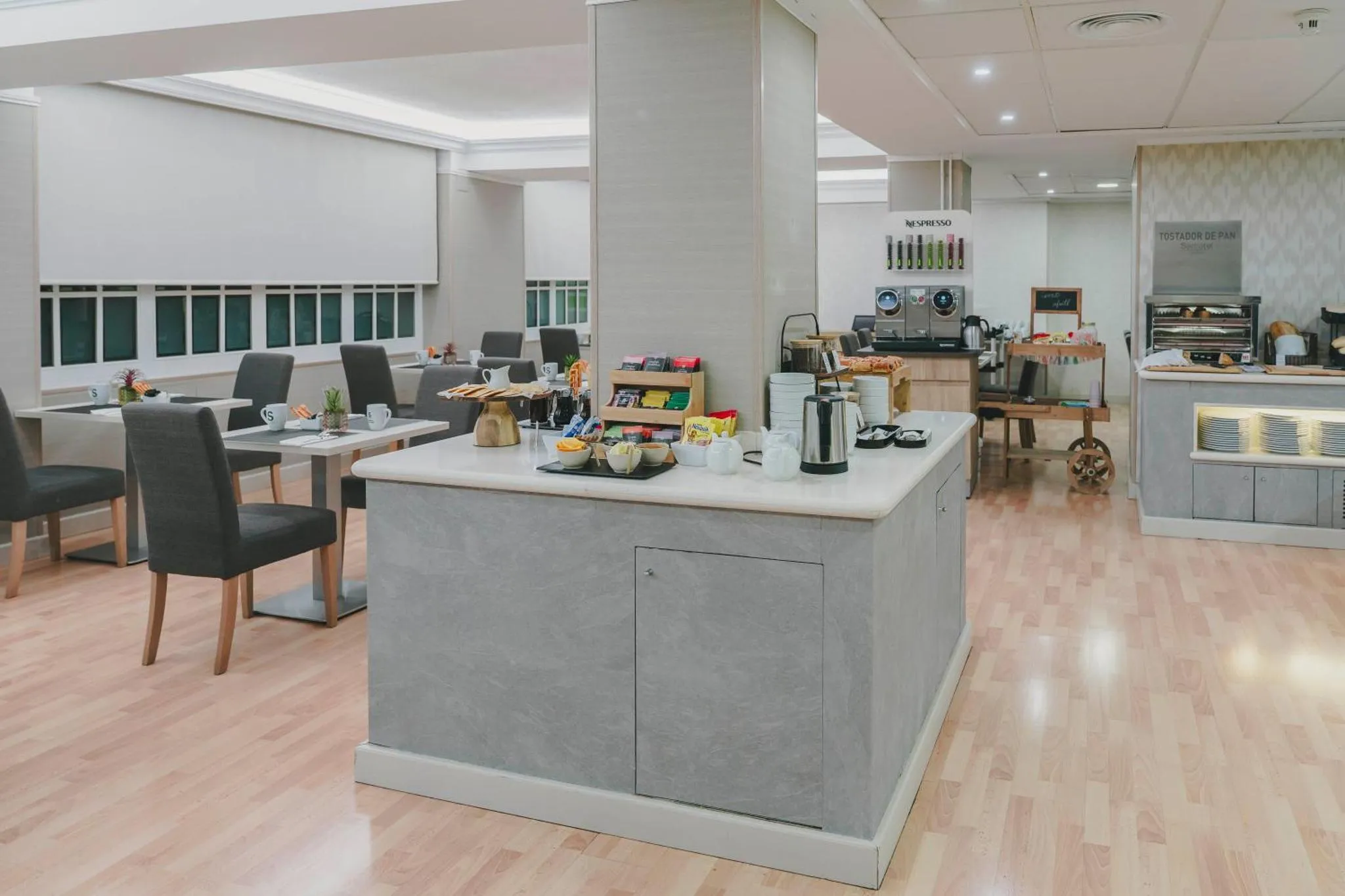 Une salle lumineuse avec un buffet propose des viennoiseries et des boissons.