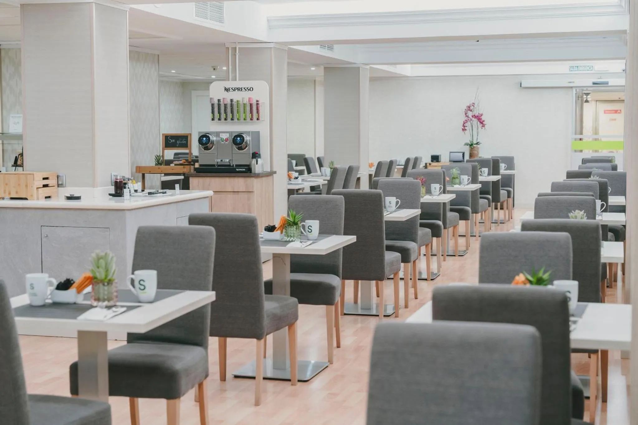 Une salle lumineuse avec des tables et des chaises grises, prête pour le service.