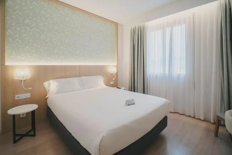 Une chambre lumineuse avec un grand lit et des rideaux clairs.