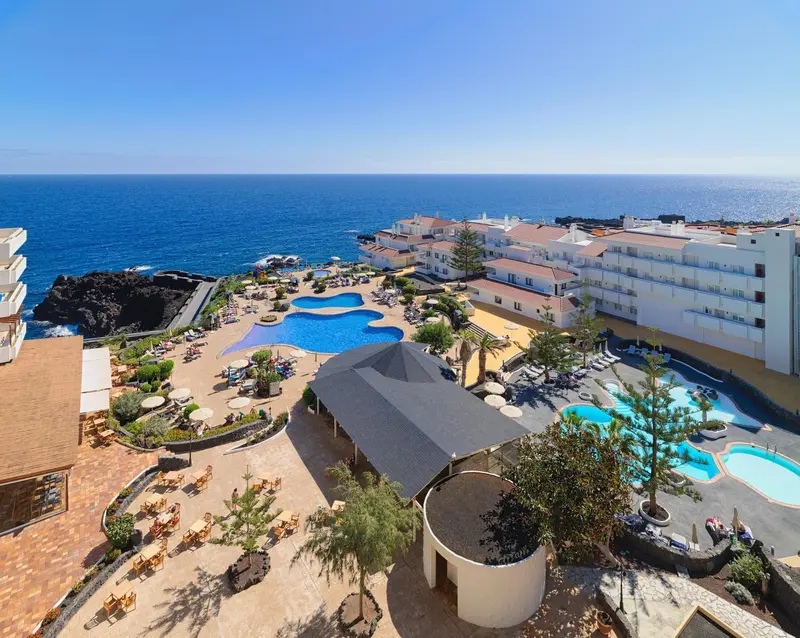Vue aérienne d'un complexe hôtelier avec piscines et accès à la mer.