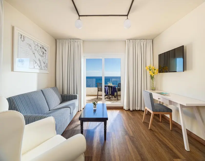 Espace de vie lumineux avec canapé, table basse et vue sur la mer.