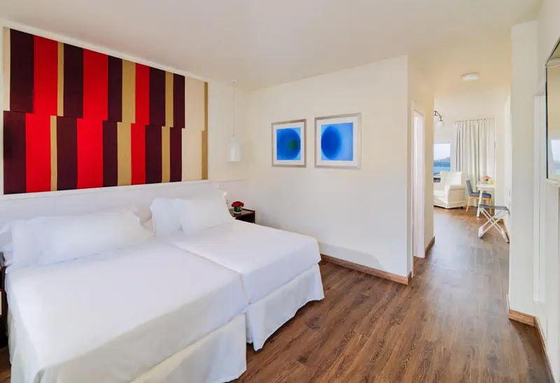 Une chambre lumineuse avec un grand lit et une décoration murale colorée.
