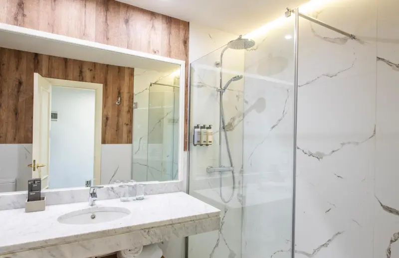 Une salle de bain moderne avec une douche à l'italienne et un grand miroir.