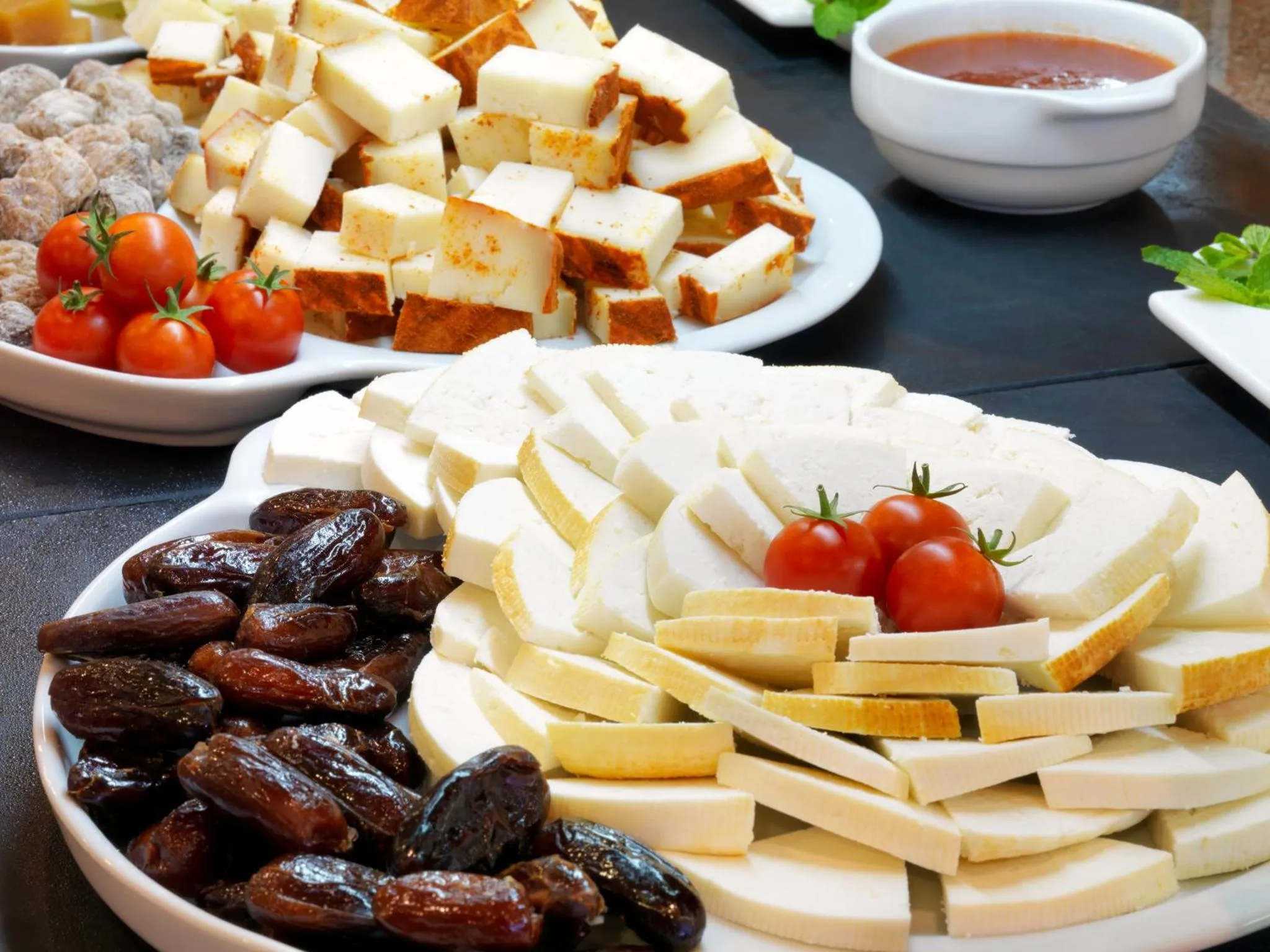 Assortiment de fromages, de légumes et de pains présentés sur des plats.