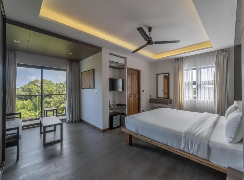 Une chambre lumineuse avec un grand lit et une vue sur la végétation.