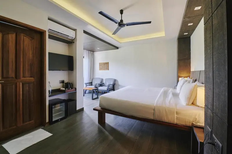 Une chambre lumineuse avec un grand lit et un espace salon.