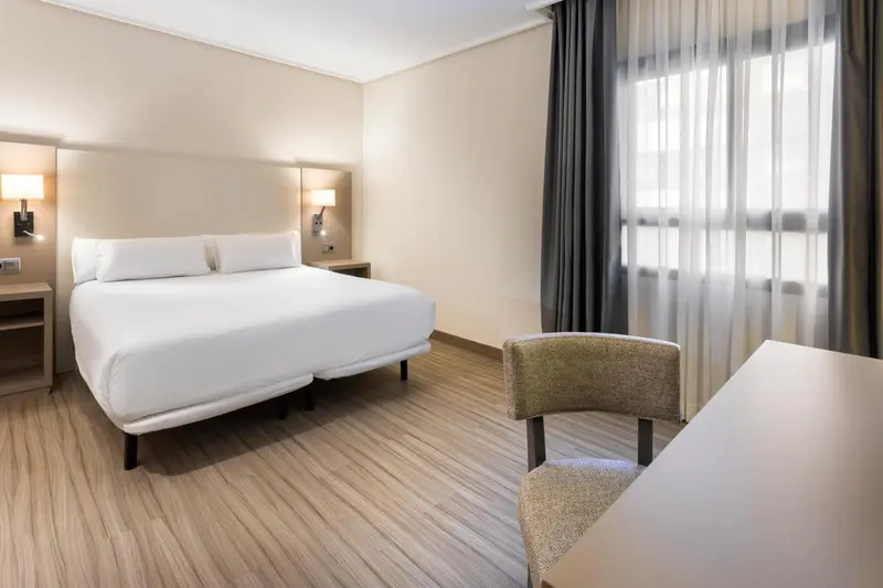 Une chambre lumineuse avec un grand lit et un bureau.