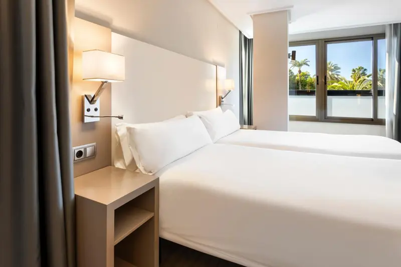 Une chambre d'hôtel lumineuse avec un grand lit et des lampes de chevet.
