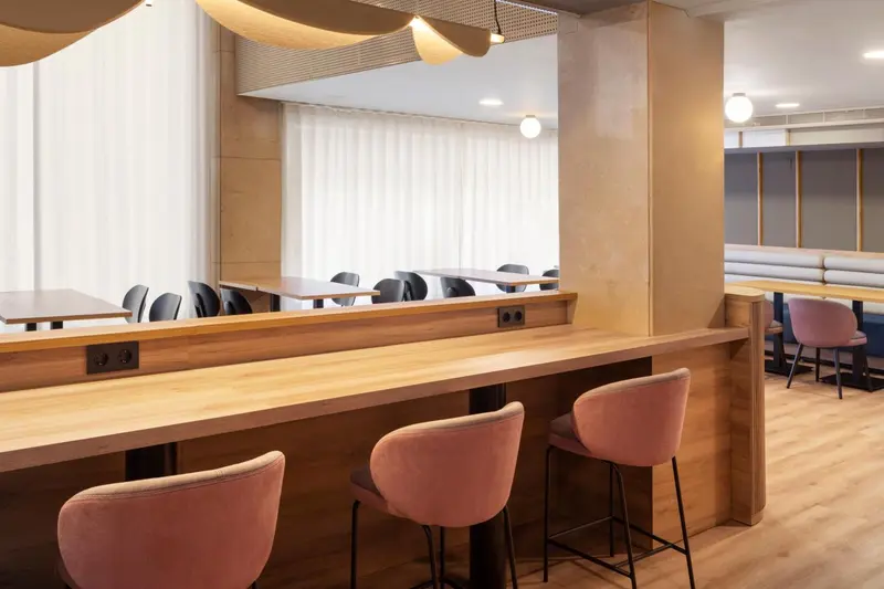 Un espace de restauration avec des tabourets et des tables en bois.
