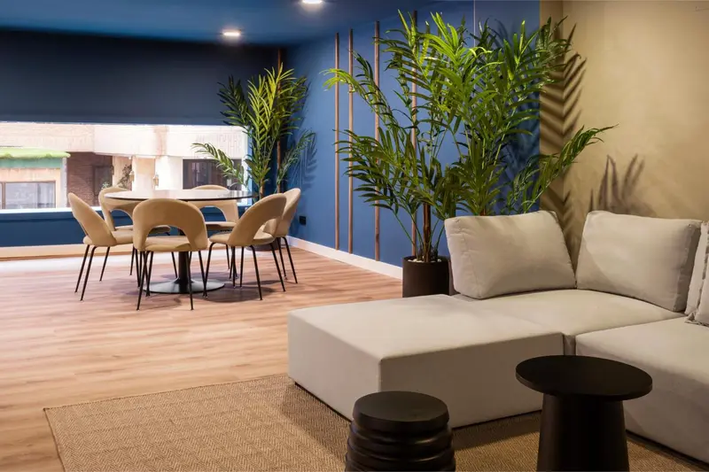 Un espace de détente avec canapés et table à manger est éclairé par la lumière naturelle.