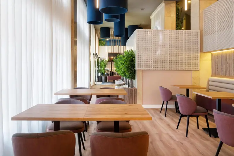 Une salle de restaurant lumineuse avec des tables et des chaises.
