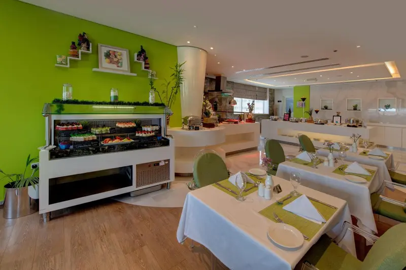 Une salle de restaurant lumineuse avec un buffet de desserts et des tables dressées.