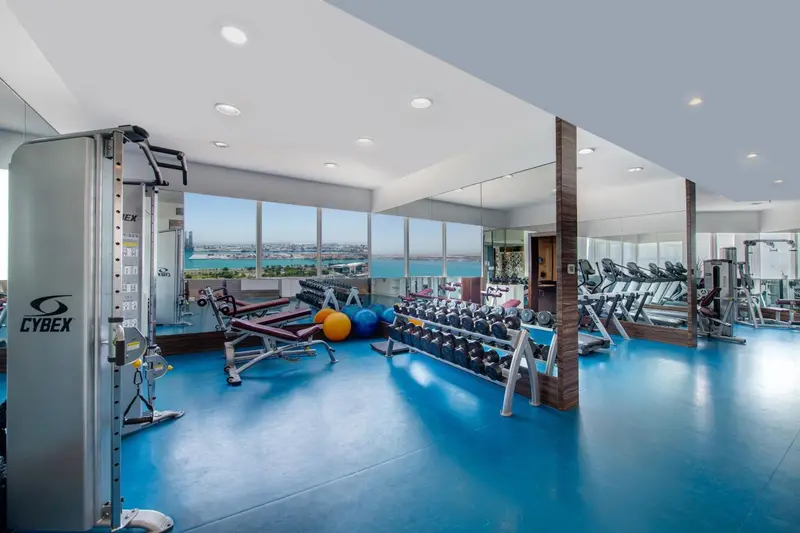 Une salle de sport lumineuse avec des équipements de musculation et une vue sur la mer.