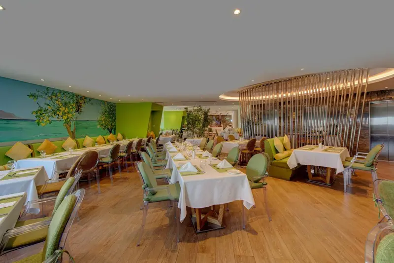 Une salle lumineuse avec des tables dressées pour un repas.