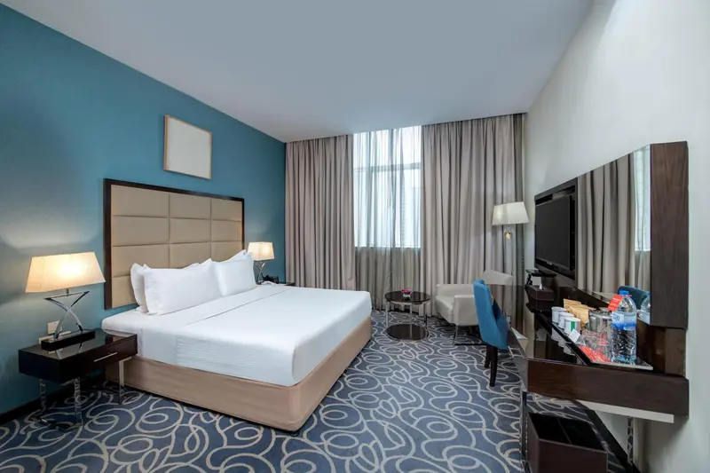 Chambre d'hôtel lumineuse avec un grand lit et un bureau.