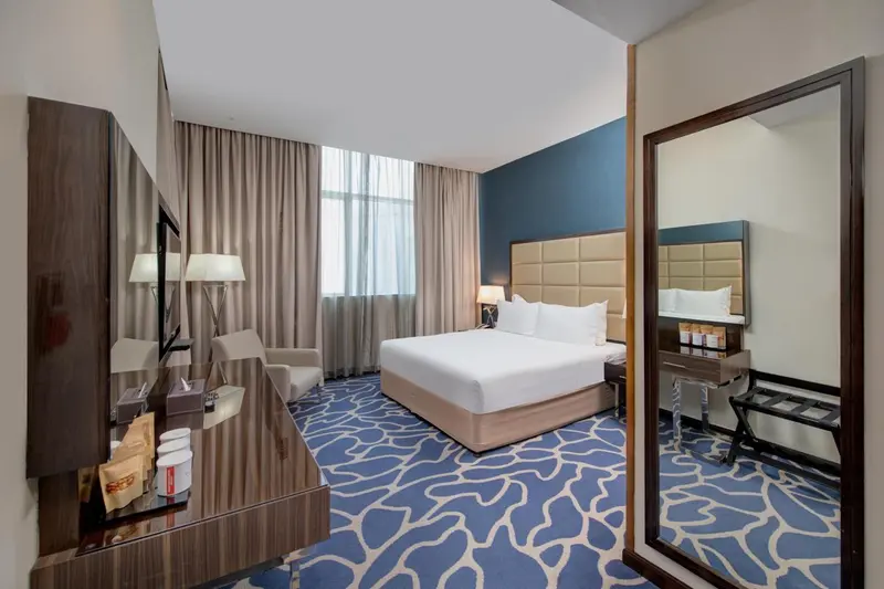 Chambre d'hôtel moderne avec un grand lit et un miroir.