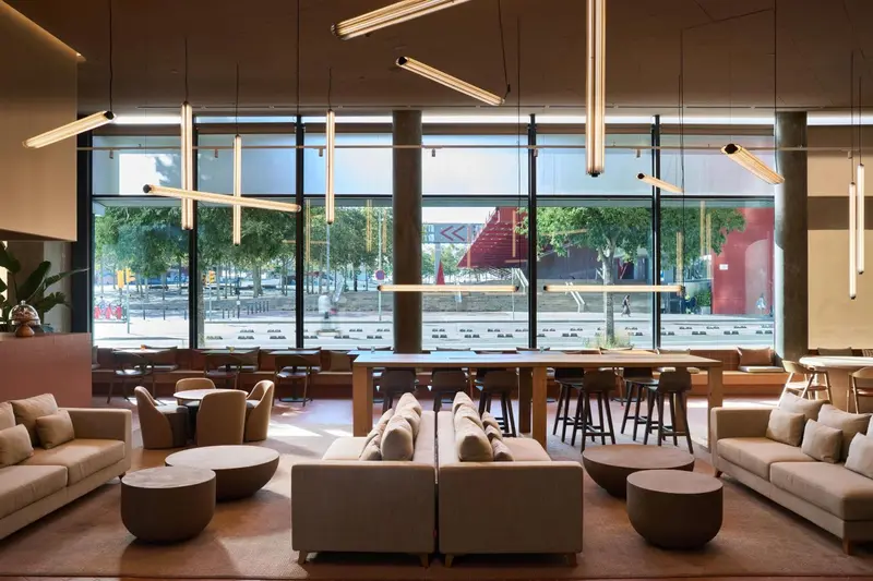Espace de détente intérieur avec canapés, tables basses et larges baies vitrées donnant sur l'extérieur.