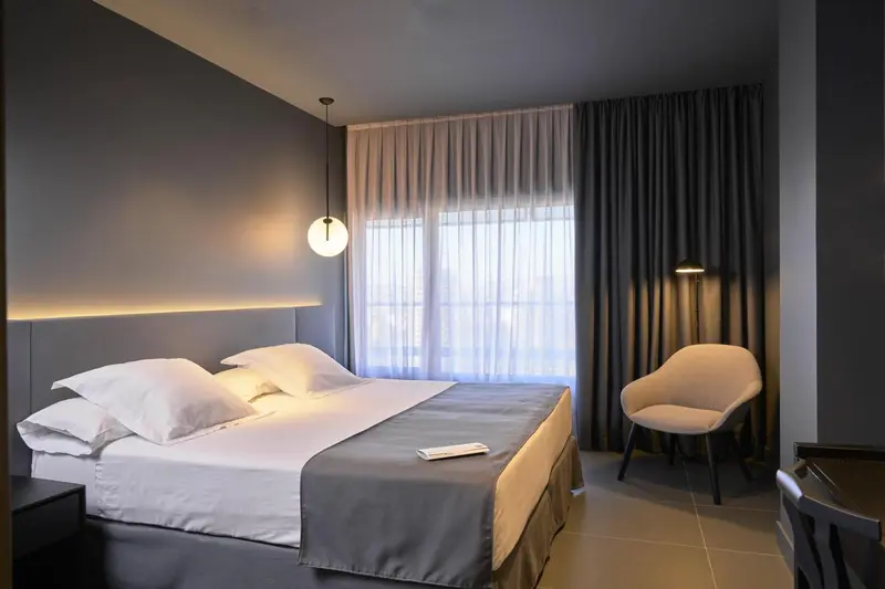 Une chambre d'hôtel moderne avec un lit double et un fauteuil.