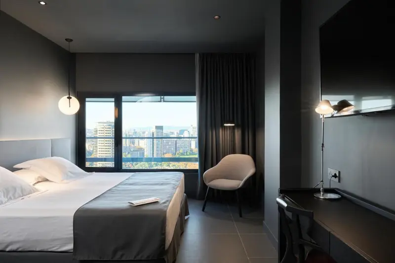 Chambre moderne avec un grand lit et une vue sur la ville.