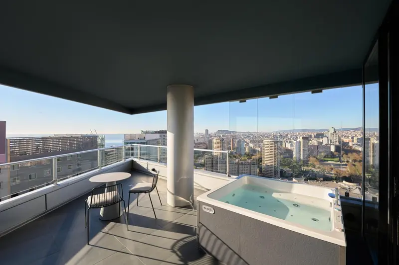 Terrasse avec jacuzzi et vue sur la ville et la mer.