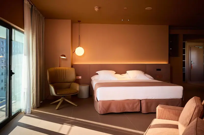 Une chambre à coucher lumineuse avec un lit double et un fauteuil.