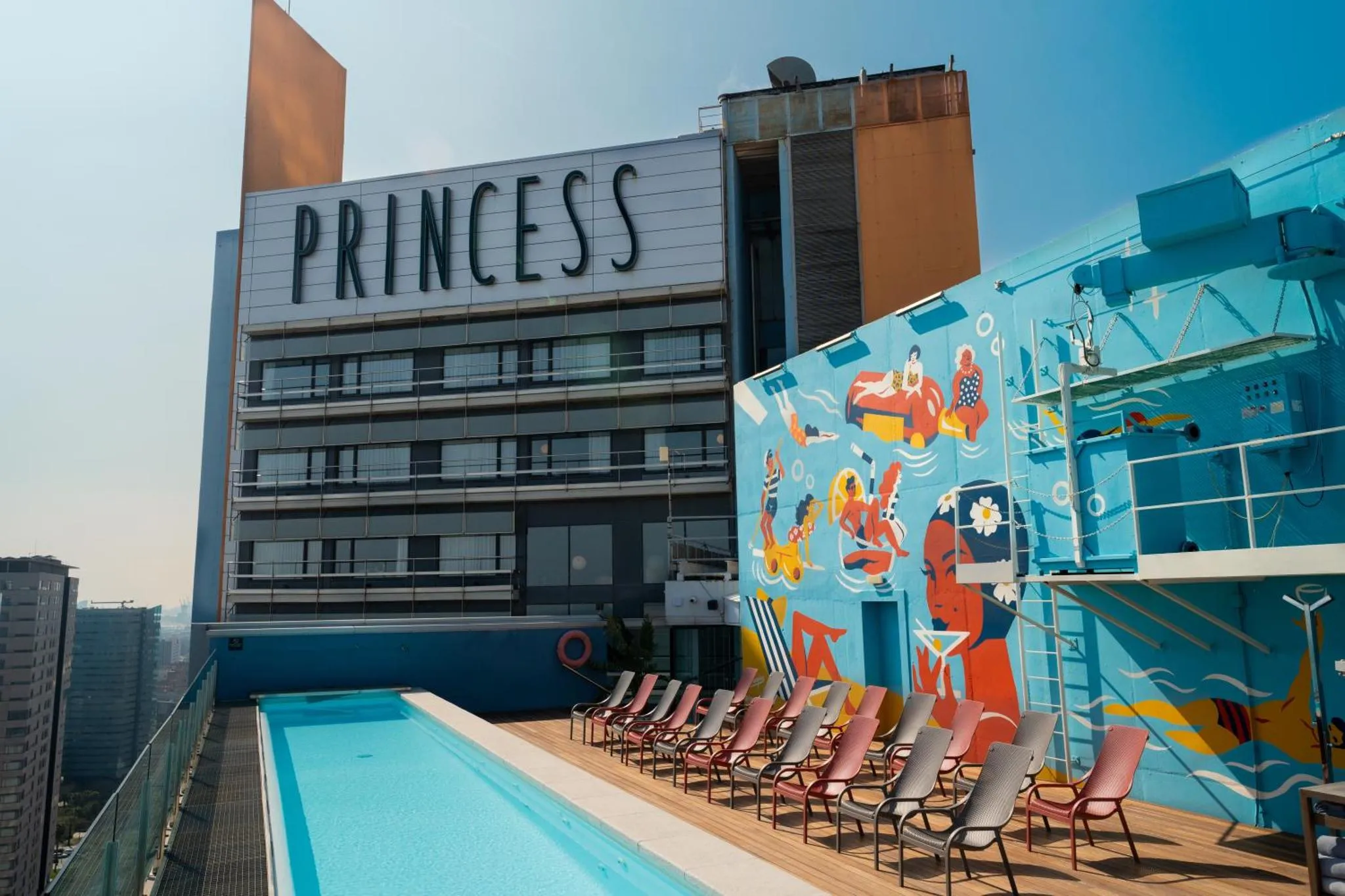 Terrasse avec piscine et chaises longues devant un bâtiment coloré.