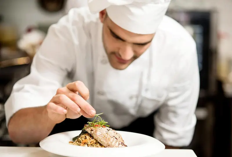Un chef prépare un plat dans une cuisine professionnelle.
