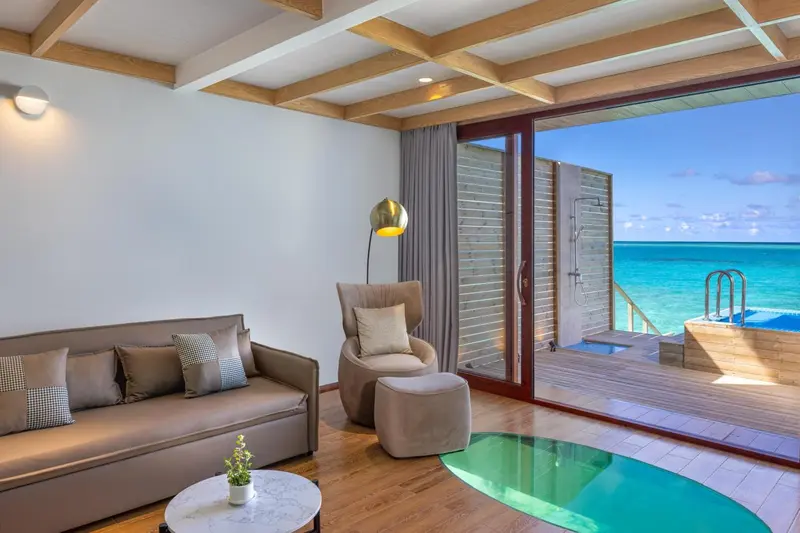 Espace de détente intérieur avec canapés et vue sur une terrasse aquatique.