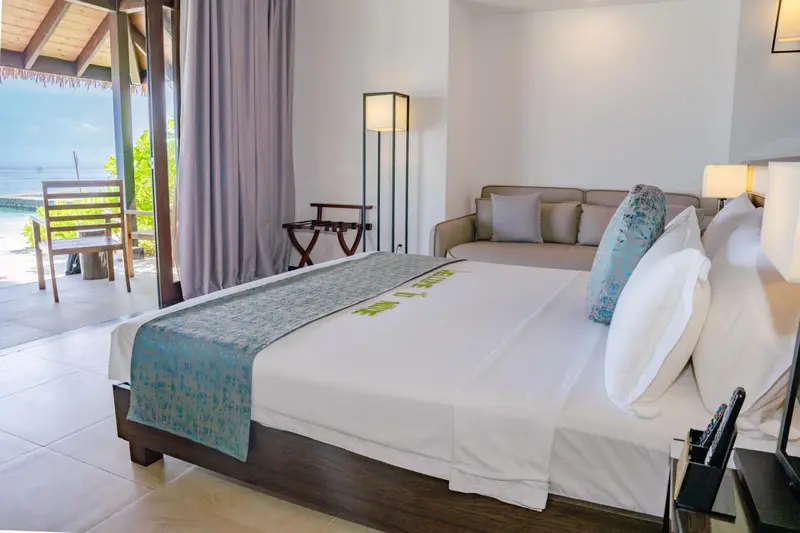 Une chambre lumineuse avec un grand lit et un canapé face à une baie vitrée.