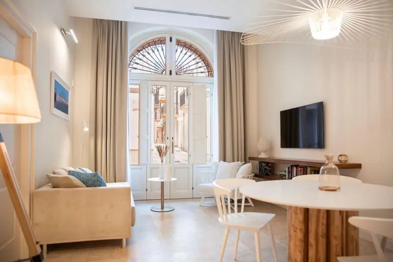 Un salon lumineux s'ouvre sur un balcon par de grandes portes cintrées.