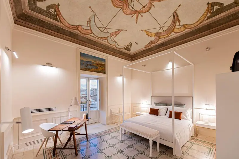 Chambre lumineuse avec un lit à baldaquin et une décoration murale peinte.
