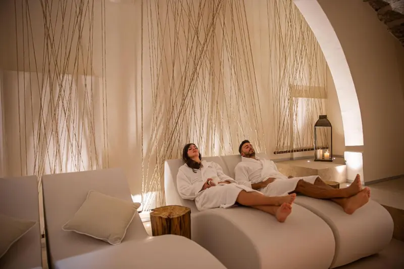 Un couple se détend sur des chaises longues dans un espace lumineux et apaisant.