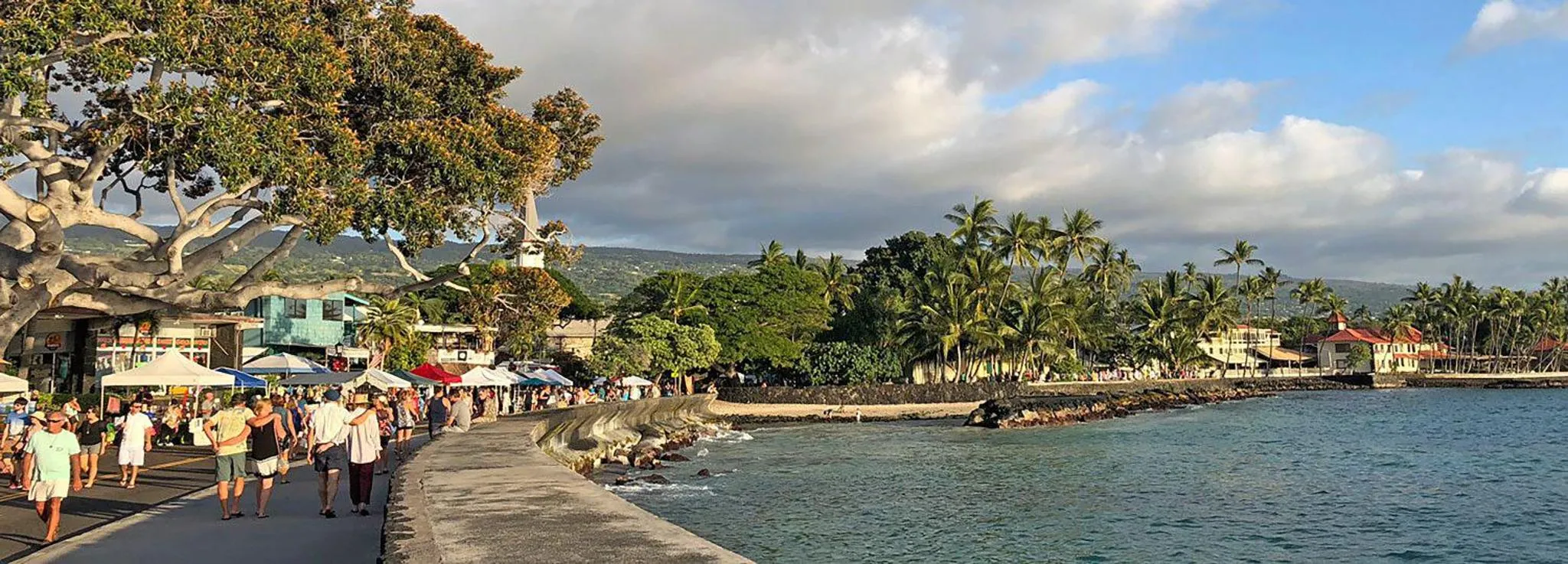 Une promenade en bord de mer avec des personnes se déplaçant le long d'une digue rocheuse.