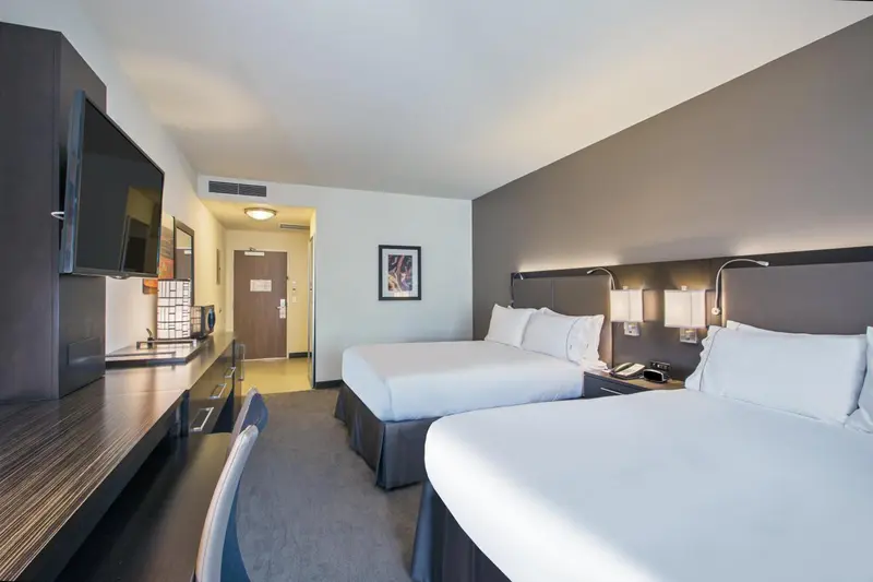 Chambre d'hôtel moderne avec deux lits et un bureau.