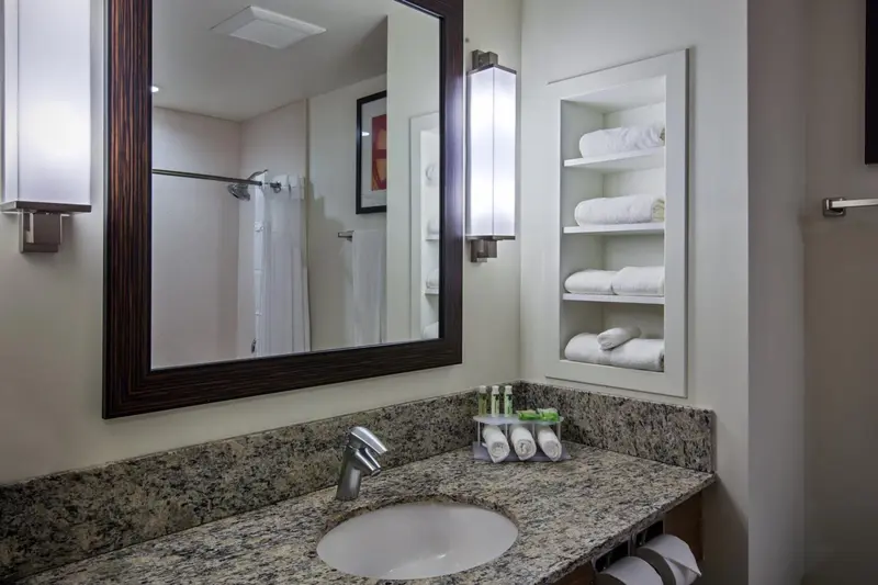Une salle de bain claire avec un grand miroir et des serviettes pliées.