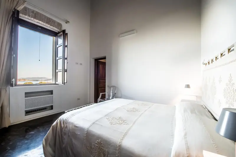 Chambre lumineuse avec un lit fait et une vue sur le paysage.