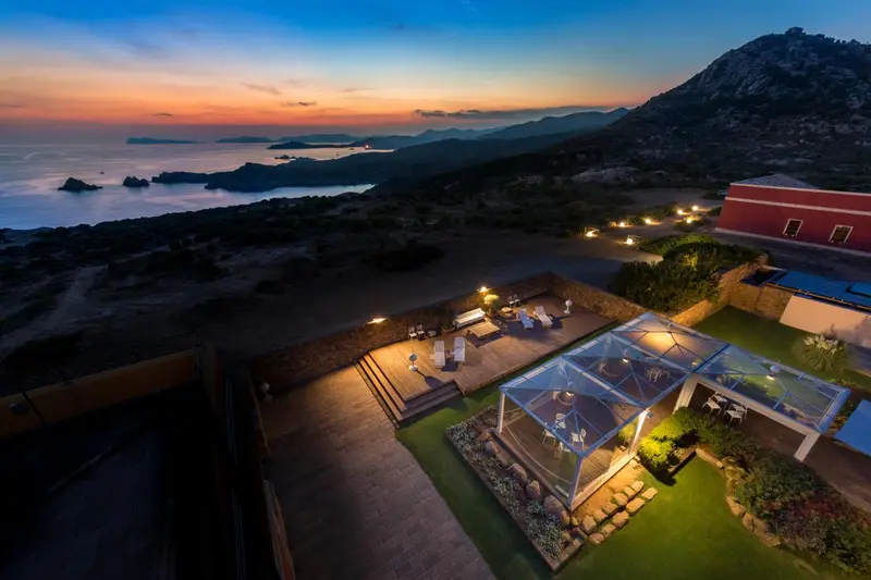 Vue aérienne d'un complexe hôtelier illuminé au crépuscule avec une terrasse et une piscine.